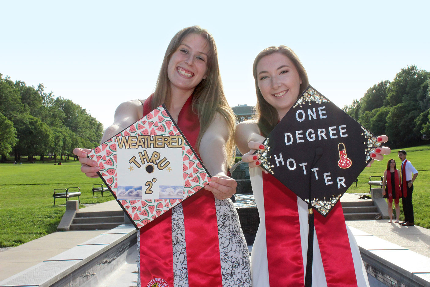 Two female AOSC graduates showing off decorated caps.