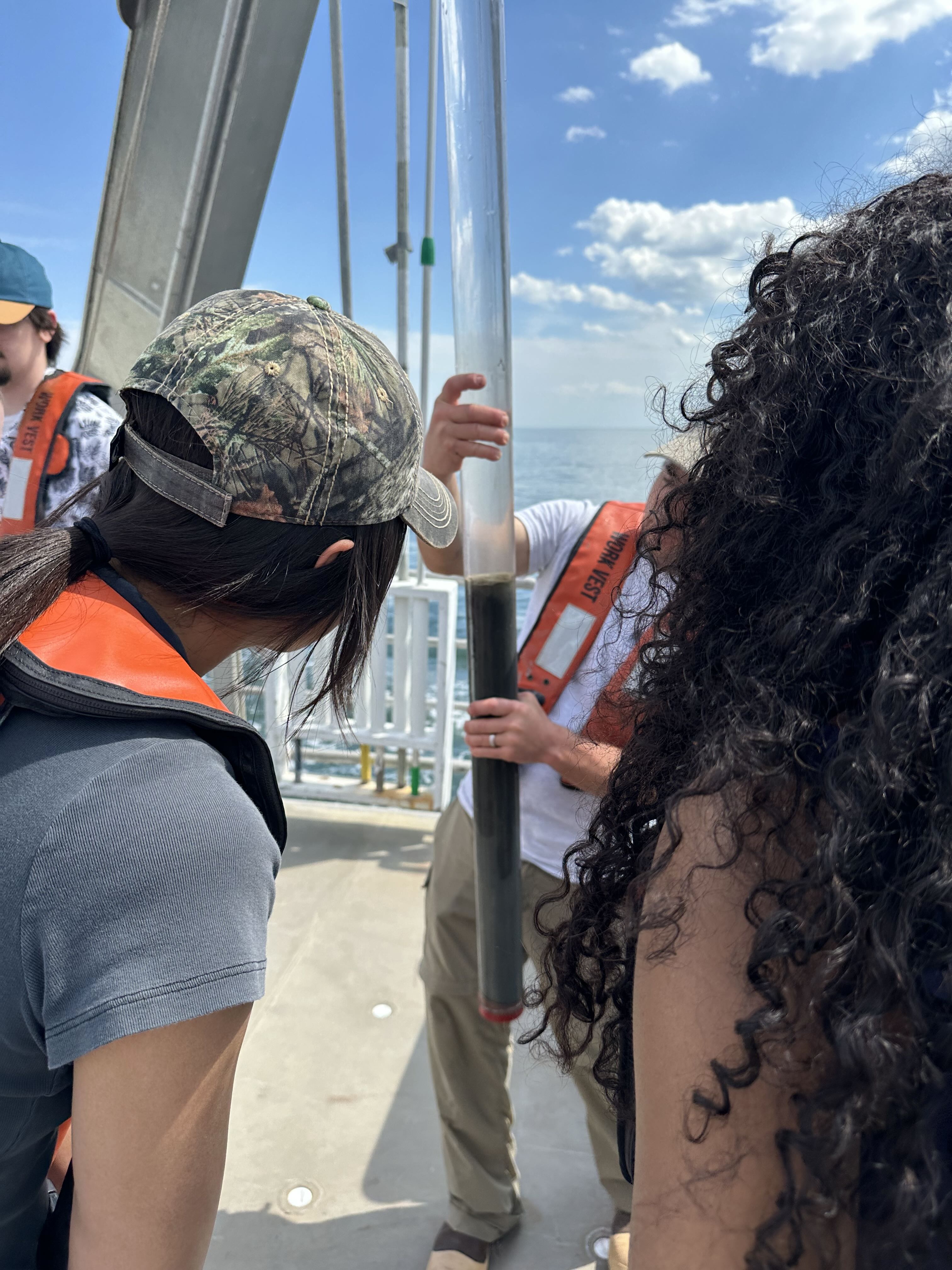 Students looking at a sea floor sediment sample in a tube