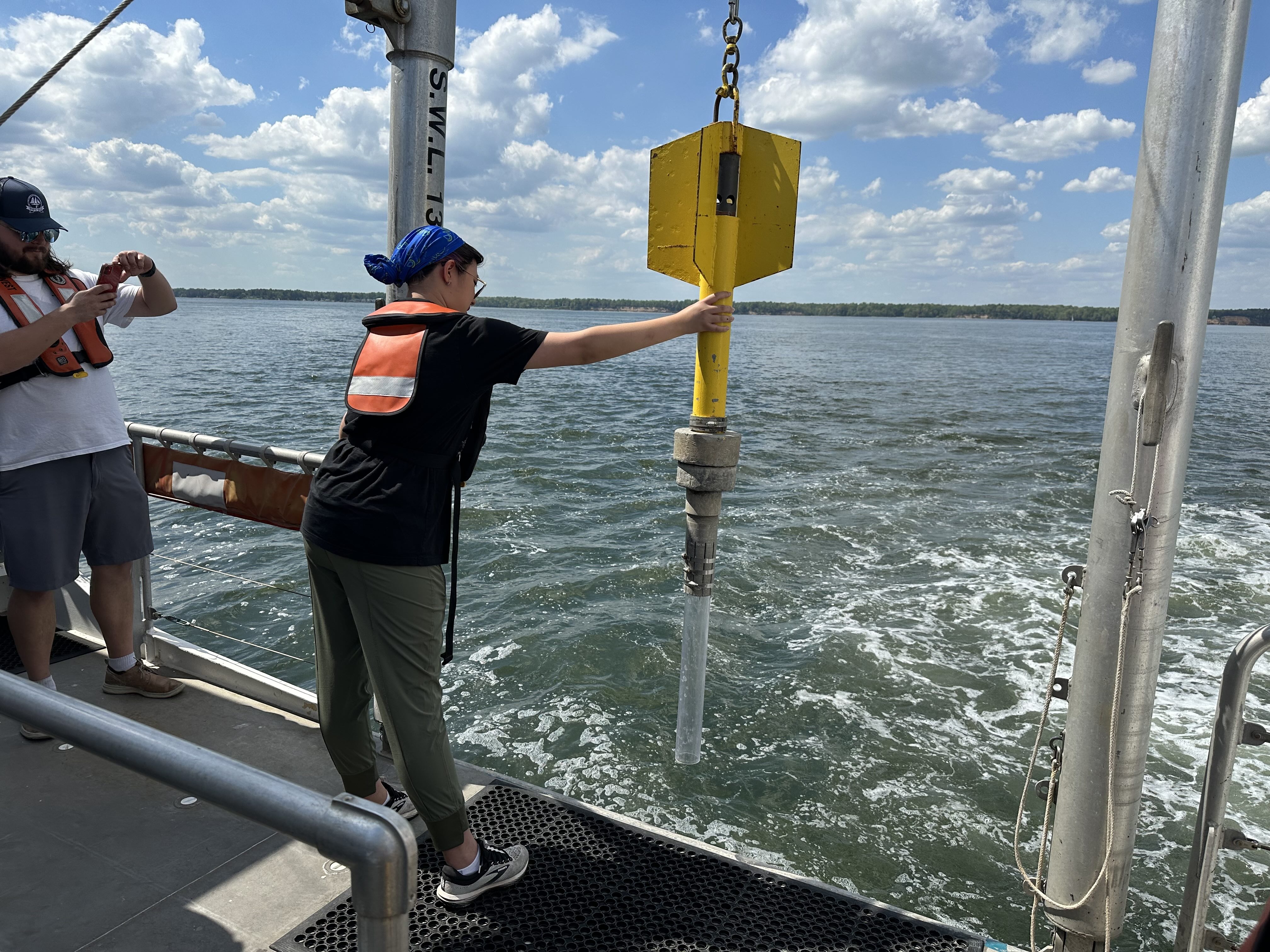 A student participating in the raising of a instrument out of the water from the ship's deck