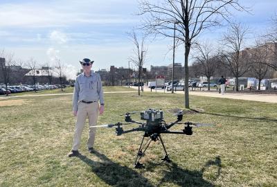 Daniel Lathrop standing next to a drone