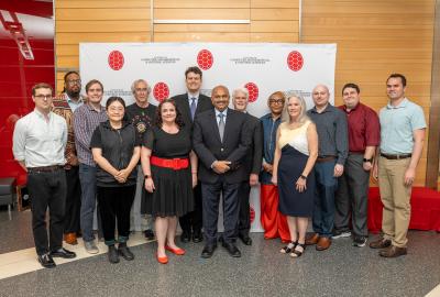 Group of employee awardees standing and smiling in front of a CMNS branded backdrop