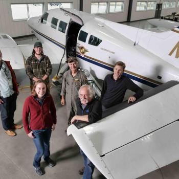 Researchers posing for photo beside aircraft