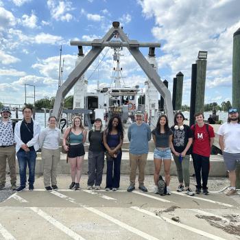 Students posing for photo on the dock in front of a ship