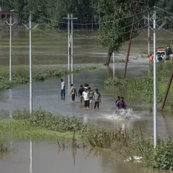 A group of people wading through a flooded road in Kashmir.